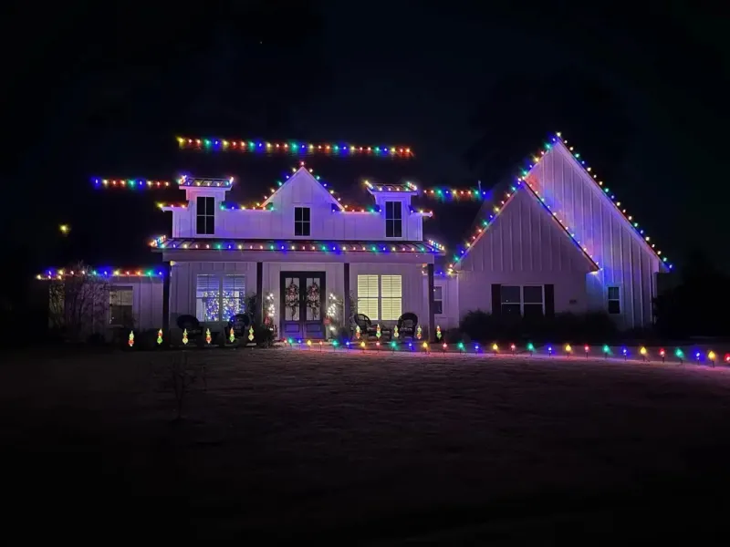 A picture showing multi-colored Christmas lights around a house.